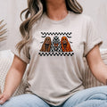 Sand Gildan Softstyle tee mockup with three retro ghosts holding lollipops between checkerboard stripes