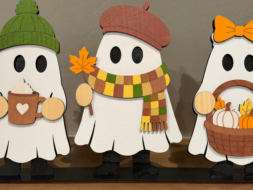 Close-up of three painted fall ghosts in beanie, beret with scarf, and bow with pumpkin basket